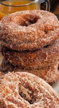 three sugared donuts stacked on top of each other next to a glass of orange juice