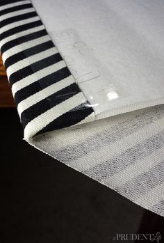 a white and black striped table cloth on top of a wooden table with a drawer in the background