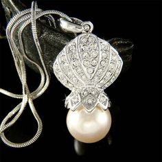 You are getting a Clear Seashell Hugging Creme White Pearl Pendant with Swarovski crystals. It comes with a FREE 18" inch (45cm) silver plated, rhodium finish snake  necklace with lobster clasp. Pendant size is 3/4" wide X 1 9/16" high (19mm X 40mm)Crystal Color: Crystal Clear ===================Prices are in US$.For shipping policies and other important information, click on “profile” on the right.See an item that you like but has already been sold? Contact me to see if I have more!Thank you fo Pearl White Rhinestone Jewelry For Gifts, Pearl Necklaces With Rhinestones For Gift, Elegant Crystal Jewelry For Birthday, Marine Jewelry, Crystal Seashells, Pearl Beach, Seashell Pendants, Seashell Necklace, Brooch Jewelry