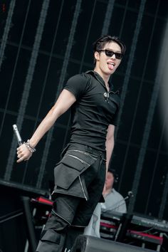 a male in a black shirt and pants on stage with his arms out to the side