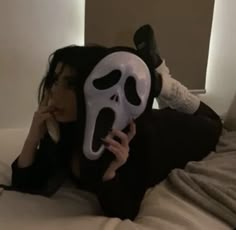 a woman laying on top of a bed with a mask covering her face and mouth