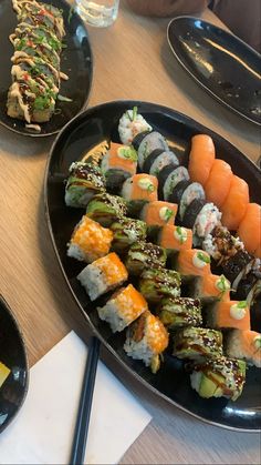 sushi on a black plate with chopsticks next to it