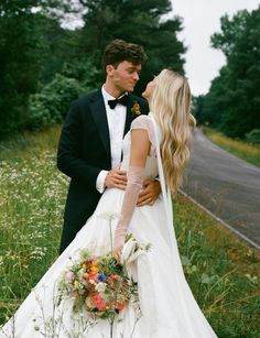 a bride and groom are standing in the grass