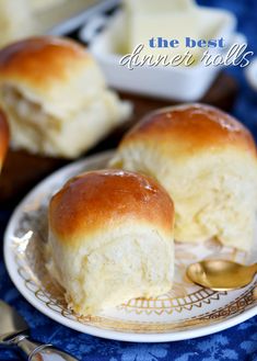 two rolls sitting on top of a white plate next to silverware and spoons