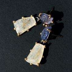 The magnificent harmony of iolite and rutilated quartz stones. In these earrings, the iolite stones are carved into beautiful leaf patterns. The golden rutile inclusions in the quartz are striking. It is normal for the sizes of the precious stones to vary.  Reminder: One of the iolite leaves is slightly smaller than the other.  Silver materials have been used.  These dangling earrings can complement a chic look or serve as a wonderful gift alternative. Iolite Stone, Leaf Patterns, Earrings Dangling, Rutile Quartz, Dangling Earrings, Quartz Earrings, Rutilated Quartz, Leaf Pattern, Precious Stones