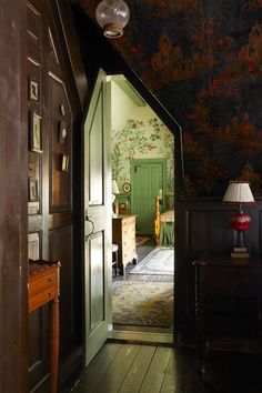 an open door leading to a bedroom with floral wallpaper on the walls and wooden floors