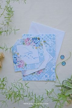 three envelopes with flowers on them sitting next to some green plants