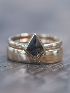 two gold wedding bands with a black diamond in the center on top of each other