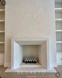 an empty fireplace in a white room with shelves