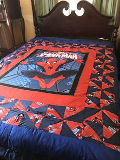 a spiderman quilt is on top of a bed with blue and red bedspread