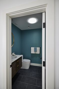 an open door leading to a bathroom with blue walls and white fixtures on the wall