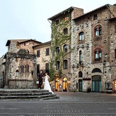 a bride and groom standing in front of an old building