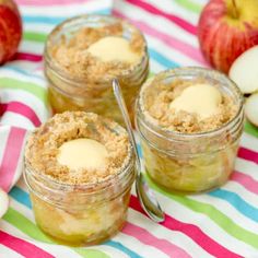 three small jars filled with food sitting on top of a table next to an apple