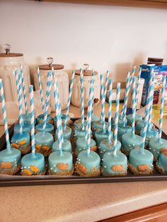 there are many cupcakes with blue and white striped straws on the top