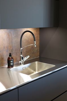 a stainless steel kitchen sink with faucet and soap dispenser next to it