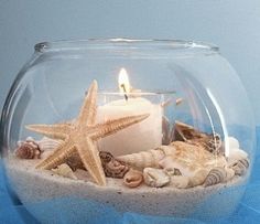 a glass bowl filled with sand and starfish on top of a blue table cloth