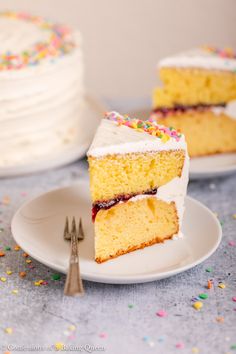 a slice of cake with white frosting and sprinkles on a plate