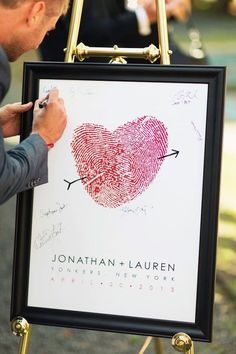 a man writing on a sign with a fingerprint in the shape of a heart