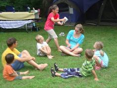 a group of children sitting on the grass playing with a frisbee in front of a tent