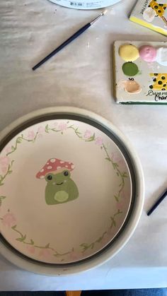 a table topped with plates and paintbrushes on top of it