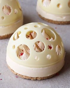 three small cakes with shells on them sitting on a counter top next to each other