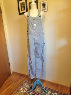 Vintage 1960's authentic Big Mac overalls are white with a vertical blue conductor stripe. Features several multi use pockets are on the front chest, button fly, two front waist pockets, two large back pockets, two pockets on the side of the right leg,  and hammer hook on the left leg. Adjustable overall straps. Union Made. 100% cotton. In excellent condition! These overalls have only slight light brown mark on the right overall strap (see picture). Priced for condition. Size Estimate M (waist 34") Make sure to allow 1"-3" allowance for comfort and movement. White Bib Front Overalls With Pockets, Casual Striped Overalls With Pockets, Striped Cotton Overalls, White Utility Overalls With Pockets, White Overalls With Pockets For Workwear, Striped Overalls Outfits, Dungarees Outfit, Overall Straps, Overalls Outfits