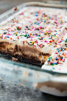 a cake with white frosting and sprinkles in a glass baking dish