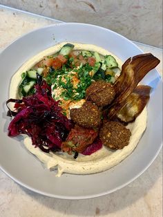 a white plate topped with meat and veggies on top of a marble counter