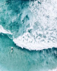 an aerial view of two surfers in the ocean