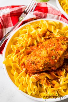 two plates of pasta with chicken parmesan sauce and a fork on the side