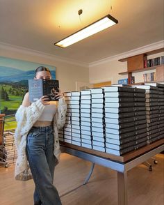 a woman standing in front of stacks of binders and holding up a large book