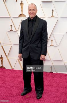 an older man in a tuxedo poses on the red carpet at the oscars