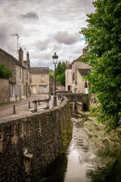 a river running through a small town next to tall buildings and a lamppost in the distance