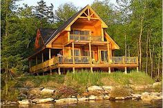 a log cabin sits on the shore of a lake