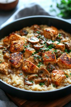 chicken and mushroom riso with mushrooms in a skillet on top of rice, garnished with parsley