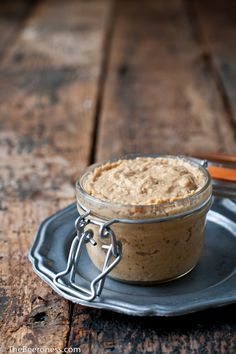 a small glass jar filled with food sitting on top of a metal plate next to a spoon