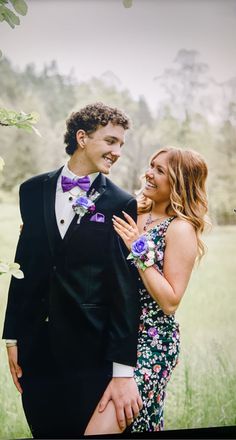 a man in a tuxedo standing next to a woman wearing a floral dress