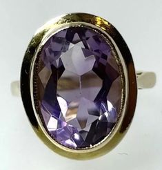 Amethyst Ring Own a piece of vintage charm with this beautiful 9ct yellow gold cocktail ring, featuring a stunning oval amethyst of 4.59 carats. The gemstone is bezel set and the stone and setting measures 17x13.6mm and it is sizeable up to J 1/2.  Crafted in the United Kingdom in 1966, this ring is a timeless piece of fine jewellery that can be worn on special occasions like Mother's Day, Christmas, Graduation, Anniversary, Birthday, and Valentine's Day. This exquisite ring is perfect for colle Timeless Yellow Gold Amethyst Ring With Oval Shape, Timeless Gold Oval Amethyst Ring, Timeless Oval Gold Amethyst Ring, Art Deco Oval Amethyst Ring, Classic Oval Amethyst Ring Collectible, Classic Gold Oval Amethyst Ring, Gold Oval Amethyst Ring In Art Deco Style, Collectible Oval Amethyst Ring In Art Deco Style, Gold Oval Amethyst Ring In Classic Style