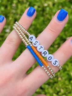 "Cheer on your favorite baseball team with this Astros gold bead bracelet set! Message me if you're interested in a set for a different team! Details: -Set includes three bracelets: Astros letter bracelet, orange color strip bracelet, blue color strip bracelet -14k gold filled beads will not tarnish -6.5\" long -3mm gold beads -7mm alphabet beads" Gold Heishi Beads Bracelets For Friendship, Gold Heishi Beads Bracelet Gift, Gold Heishi Beads Bracelets As Gift, Gold Heishi Beads Jewelry, Gold Stretch Bangle With Letter Beads, Gold Stretch Bangle Bracelet With Letter Beads, Personalized Heishi Beads Jewelry For Friendship, Friendship Jewelry With Letter And Heishi Beads, Gold Beaded Bracelets With Spacer Beads For Friendship