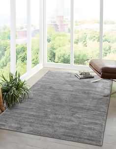 a living room area with large windows and a gray rug on the floor next to a chair