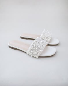 two pairs of white shoes with pearls on them