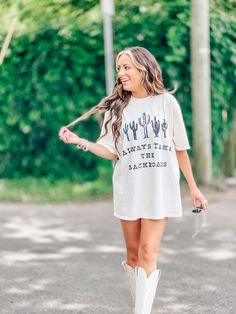 a woman walking down the street wearing white boots and a t - shirt with cactus print