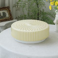 a round cake sitting on top of a table next to a vase with yellow flowers