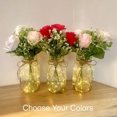 three mason jars with roses and greenery in them