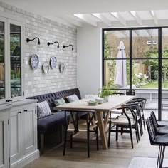 a dining room with white brick walls and black chairs around a table that has plates on it