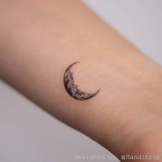 a small crescent moon tattoo on the left forearm and right arm is shown in black ink