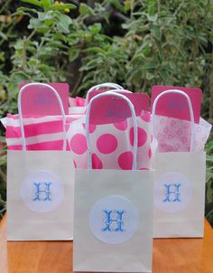 four bags with monogrammed handles are sitting on a table in front of some bushes