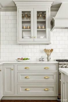 a kitchen with white cabinets and gold pulls on the cupboards is pictured in this image