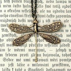 a necklace with a dragonfly on it sitting on top of a page of paper