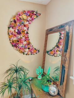 a mirror sitting on top of a wooden table next to a potted plant in front of it